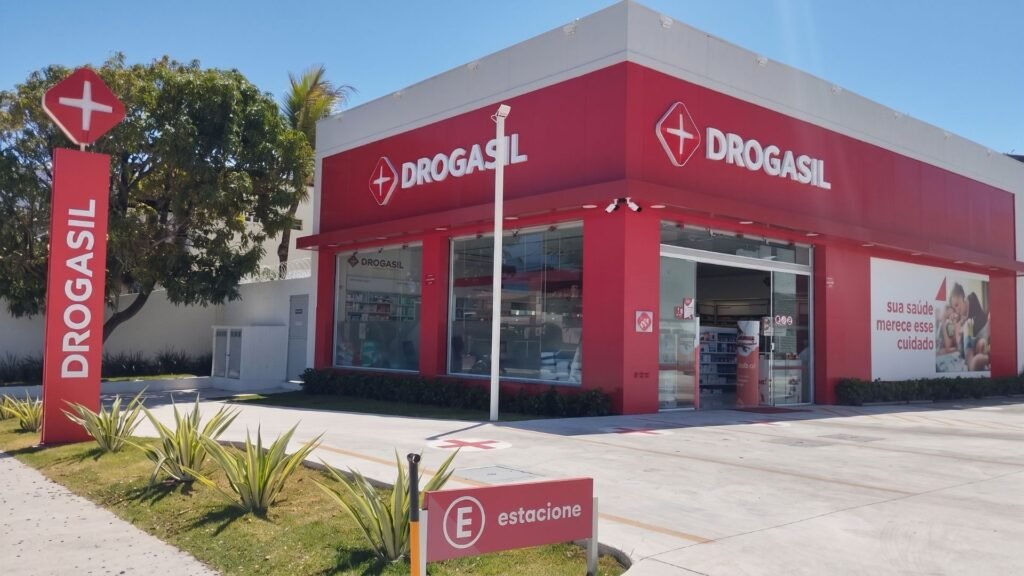 Imagem de uma farmácia com clientes e prateleiras de medicamentos