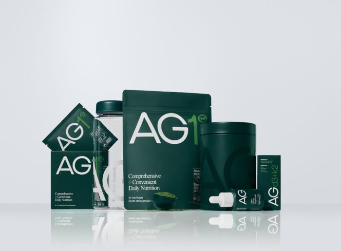 Bebida nutricional AG1 da Athletic Greens em um copo sobre uma mesa, com ingredientes ao fundo.